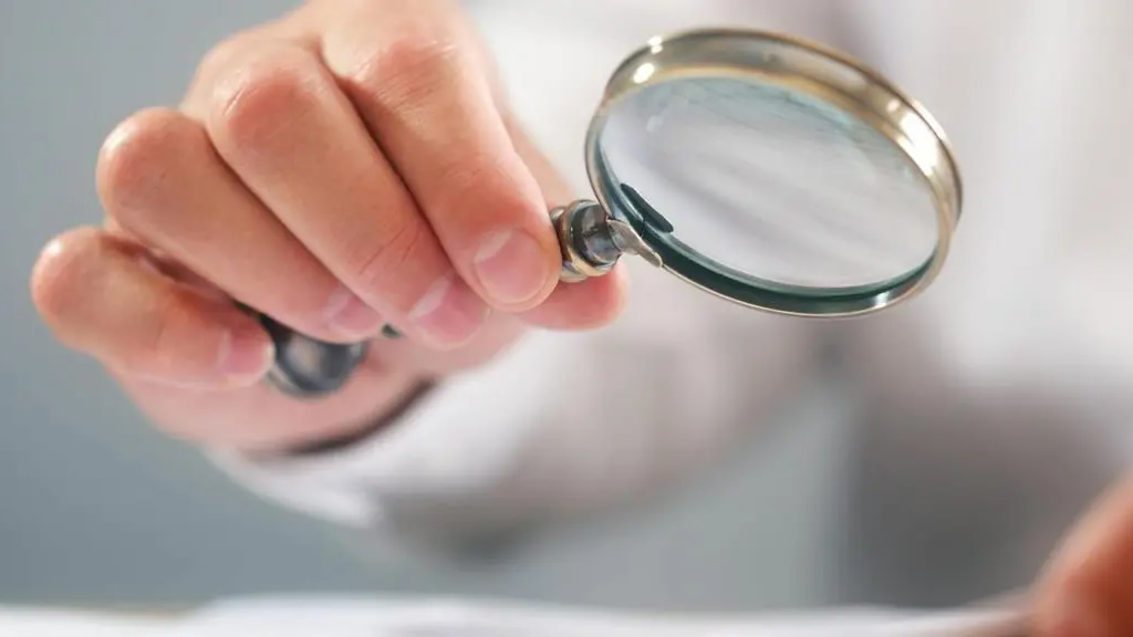 person looking at fees charged with a magnifying glass