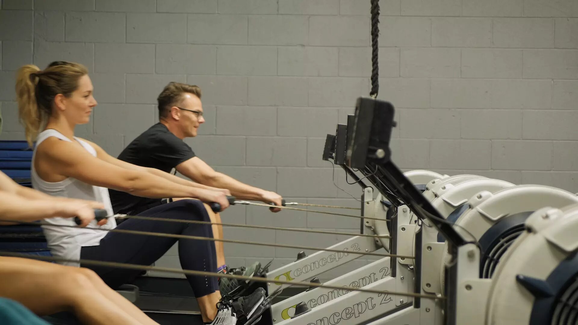a few people exercising on rowing machines