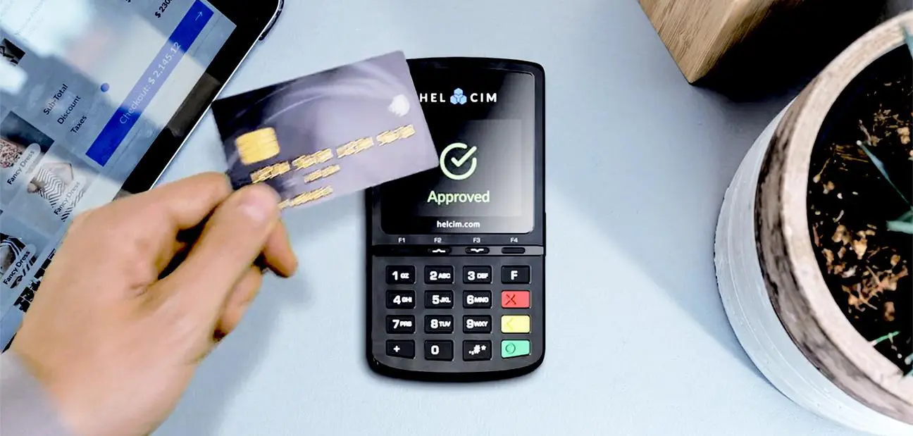 Customer hovering a credit card above a Helcim card reader- reading approved